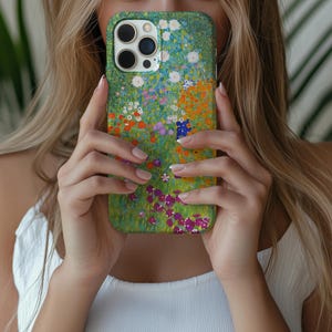 May include: A green phone case featuring a colorful floral design with white, orange, purple, and blue flowers. The case has a glossy finish and a protective bumper around the edges. The case is designed for a smartphone.