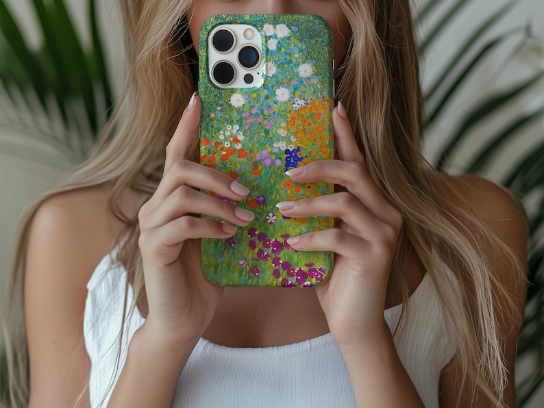 May include: A green phone case featuring a colorful floral design with white, orange, purple, and blue flowers. The case has a glossy finish and a protective bumper around the edges. The case is designed for a smartphone.