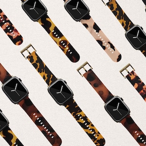 May include: Multiple watch straps with a leopard print pattern in shades of brown, black, and white. The straps are made of a flexible material and have a gold buckle.