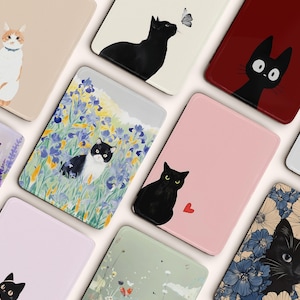 Può includere: Una collezione di oggetti decorativi a tema gatto. I disegni presentano varie illustrazioni di gatti, tra cui un gatto nero con una farfalla, un gatto in un campo di fiori e un gatto con un cuore. La tavolozza dei colori comprende rosa, beige e motivi floreali.
