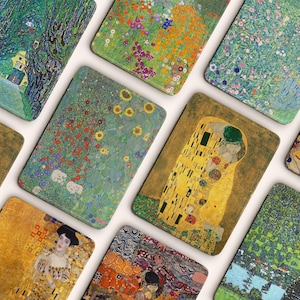 May include: A collection of rectangular art prints featuring various paintings by Gustav Klimt. The prints showcase vibrant colors and intricate details, with subjects including landscapes, floral patterns, and portraits. The artwork is displayed on a light background.
