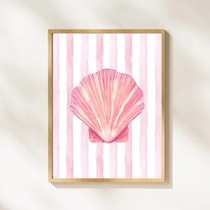 Pode incluir: Uma concha rosa com efeito aquarela sobre um fundo listrado rosa e branco. A concha está em uma moldura de madeira.