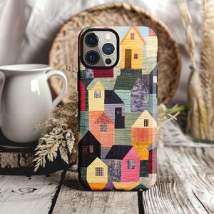 May include: A colorful phone case with a patchwork design featuring various shades of blue, red, yellow, and green. The case has a geometric pattern of houses and squares.