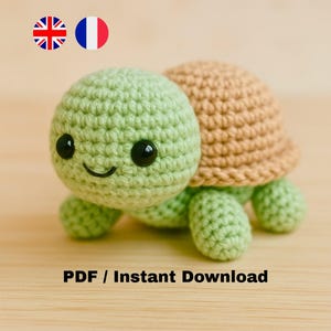 Peut inclure: Une tortue crochetée avec une tête et des membres vert clair, et une carapace beige. La tortue a des yeux noirs et une bouche souriante. Le texte "PDF / Instant Download" est en bas de l'image.