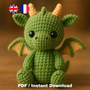 Peut inclure: Un dragon vert crocheté à la main avec des cornes et des ailes jaunes. Le dragon a de grands yeux noirs. Le texte "PDF / Instant Download" est au bas de l'image.