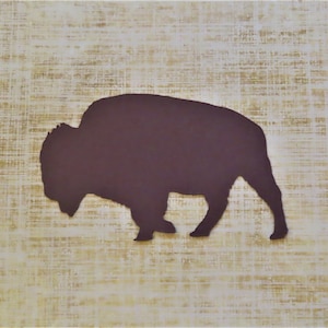 May include: A brown silhouette of a bison on a beige textured background.