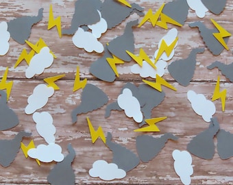 May include: A collection of grey clouds and yellow lightning bolt confetti. The confetti is scattered on a wooden surface.