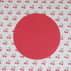 May include: A bright red circle on a background of white polka dots with a pattern of red cherries with green stems and leaves.