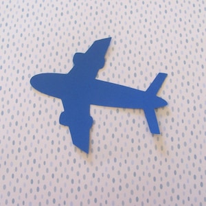 May include: A blue paper airplane cutout on a white background with blue polka dots.