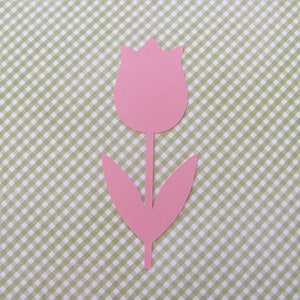 May include: A pink paper cutout of a tulip flower with a stem and two leaves against a green and white gingham background.
