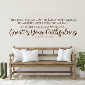 May include: A wooden bench with two white pillows and a green plant in a white pot. The wall behind the bench has a brown text quote that reads "THE STEADFAST LOVE OF THE LORD NEVER CEASES; HIS MERCIES NEVER COME TO AN END; THEY ARE NEW EVERY MORNING; Great is Your Faithfulness. LAMENTATIONS 3:22-23"