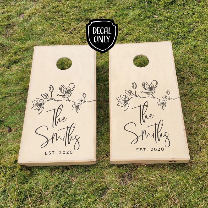 May include: Two wooden cornhole boards with a floral design and the text "The Smiths Est. 2020" on each board.