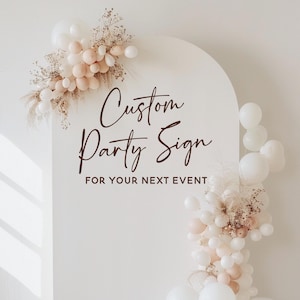 Puede incluir: Cartel de fiesta blanco arqueado con el texto "Custom Party Sign FOR YOUR NEXT EVENT" en fuente marr&oacute;n. El cartel est&aacute; decorado con globos blancos y melocot&oacute;n y arreglos florales secos.