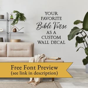 May include: A white wall with a black vinyl decal that reads "YOUR FAVORITE Bible Verse AS A CUSTOM WALL DECAL". The decal is in a living room setting with a couch, a plant, and a shelf with decorative items.