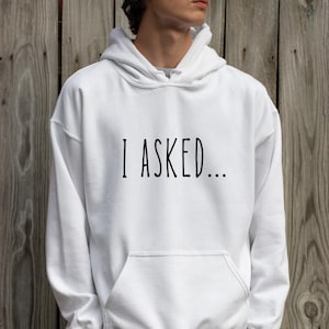 A person wearing a white hoodie with the text "I asked..." printed on it.