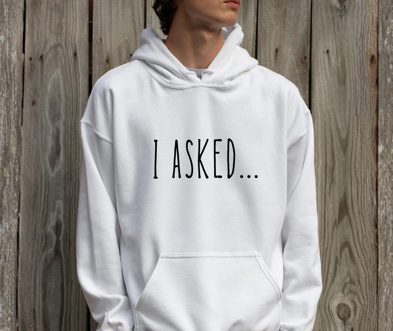 A person wearing a white hoodie with the text "I asked..." printed on it.