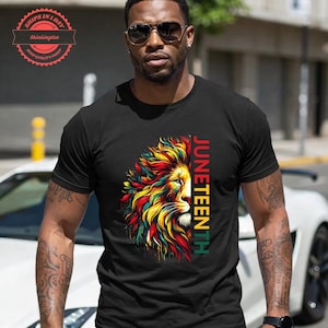May include: Black t-shirt with a vibrant lion design in red, yellow, and green. The word "JUNETEENTH" is printed vertically on the right. The shirt has a crew neck and is a casual wear item.