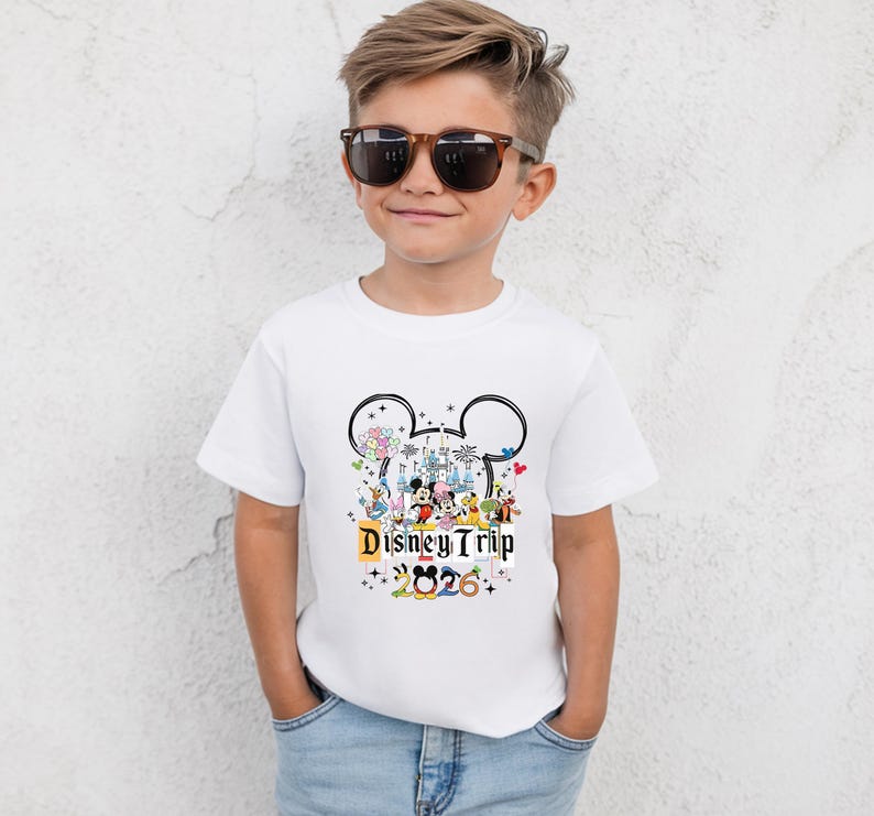 A young boy wearing a white t-shirt with a Disney-themed graphic and sunglasses, smiling at the camera.
