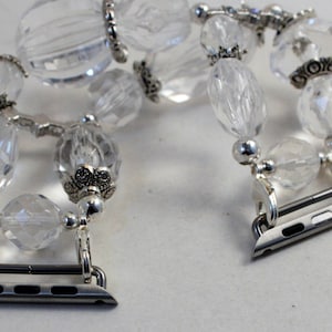 May include: A clear crystal beaded Apple Watch band with silver metal accents and connectors.
