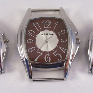 May include: Three silver-toned wristwatches with brown faces. The watches have Roman numeral hour markers and a silver-toned band.
