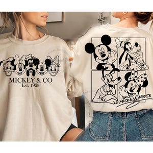 Puede incluir: Una sudadera beige con un estampado gráfico negro de Mickey Mouse y sus amigos. El texto "MICKEY & CO Est. 1928" está impreso en la parte delantera de la sudadera. La parte trasera de la sudadera presenta un estampado gráfico en blanco y negro de Mickey Mouse, Minnie Mouse, Goofy y Pluto.