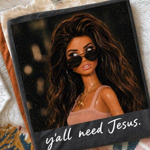 May include: A dark gray t-shirt featuring a graphic print of a doll with long wavy brown hair, wearing black sunglasses and a gold chain necklace. The doll wears a pink tank top. The white text at the bottom reads, y'all need Jesus.