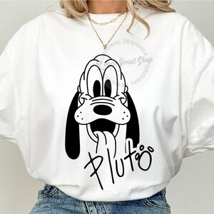 May include: White t-shirt with a black and white illustration of Pluto, the Disney dog, with the text "Pluto" underneath. The shirt has a crew neck and short sleeves.