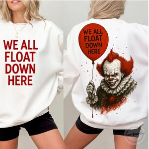 May include: White sweatshirt with the text "WE ALL FLOAT DOWN HERE" in red on the front. The back features a red balloon with the same text and a graphic of a smiling clown with red hair.