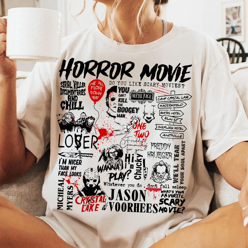 May include: White t-shirt with a graphic design featuring the words "HORROR MOVIE" and various horror movie references, including characters and locations. The design is in black and red.