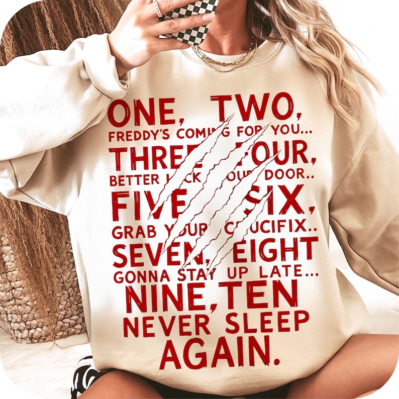 May include: Beige sweatshirt with red text: "ONE, TWO, FREDDY'S COMING FOR YOU... THREE, FOUR, BETTER LOCK YOUR DOOR... FIVE, SIX, GRAB YOUR CRUCIFIX... SEVEN, EIGHT, GONNA STAY UP LATE... NINE, TEN, NEVER SLEEP AGAIN." Claw marks are printed on the front.