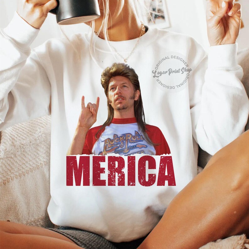 May include: White sweatshirt featuring a red, white and blue graphic of a man with long blonde hair and a goatee. The graphic says "Merica" and "Rock & Roll" on the shirt. The sweatshirt has a small circle with the text "Original Designer Logan Print Shop Original Designer".