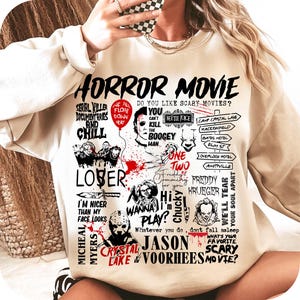 May include: Beige sweatshirt with a graphic design featuring the text "HORROR MOVIE" and various horror movie characters and references. Includes text like "SERIAL KILLER DOCUMENTARIES AND CHILL" and "CRYSTAL LAKE".