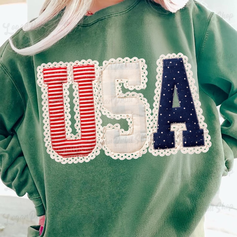 Puede incluir: Sudadera verde con la palabra "USA" aplicada en la parte delantera. Las letras son de rayas rojas y blancas, cuadros blancos y azul marino con lunares blancos, todo ribeteado con encaje blanco.