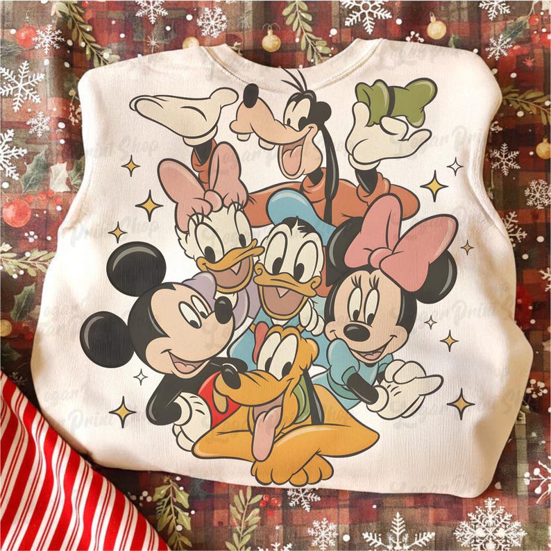 May include: White sleeveless shirt featuring a colorful graphic of Disney characters Mickey Mouse, Minnie Mouse, Donald Duck, Daisy Duck, Goofy, and Pluto. The design includes yellow star accents. The shirt is likely made of a soft fabric.