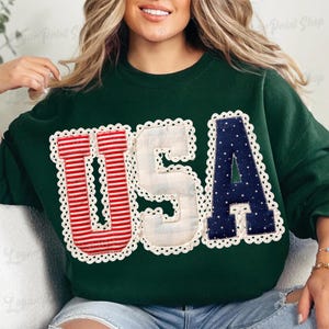 Puede incluir: Sudadera verde oscuro con la palabra "USA" en letras aplicadas blancas, rojas y azules. Las letras est&aacute;n delineadas con un ribete de encaje blanco. La "U" es a rayas rojas y blancas, la "S" es blanca y la "A" es azul marino con lunares blancos.