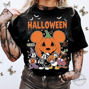 May include: Black Halloween t-shirt featuring a large orange pumpkin with Mickey Mouse ears and the word "HALLOWEEN" in orange. Below the pumpkin are cartoon characters in Halloween costumes. The shirt has the text "NOT-SO-SCARY" and "EST. 1971".