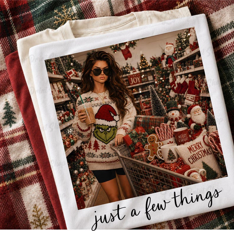 May include: A white t-shirt featuring a graphic print of a person wearing a Grinch-themed sweater and holding a drink in a store filled with Christmas decorations. The text "just a few things" is printed in black cursive script at the bottom.