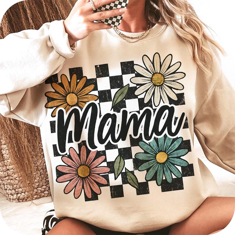 May include: A cream-colored sweatshirt with a checkered pattern and floral designs. The text "Mama" is printed in black on the front of the sweatshirt.