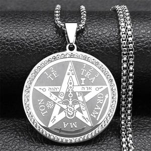 May include: A silver-toned circular pendant necklace featuring a central pentagram design with a caduceus symbol, Hebrew characters, and the text TETRAGRAMMATON. The outer edge of the pendant is lined with small clear crystals on a box chain.
