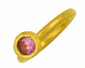 Puede incluir: Un anillo de oro con textura martillada y una piedra preciosa rosa engastada en un engaste de bisel.