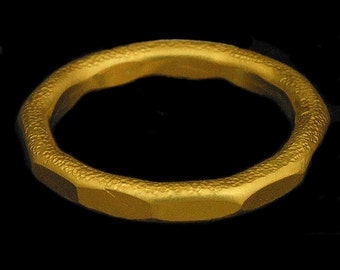 May include: A gold ring with a textured surface. The ring is simple and has a smooth, rounded shape.
