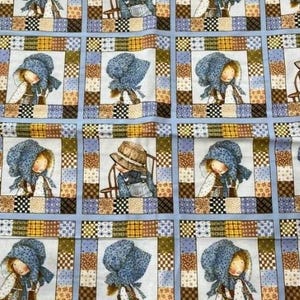 May include: A repeating pattern on fabric featuring illustrations of children in bonnets and hats, set within patchwork squares. The colour palette includes blues, browns, and yellows, creating a quilt-like appearance.