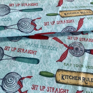 May include: A turquoise fabric with a repeating pattern of kitchen utensils and the text "Thank the cook", "Sit up straight", "Eat your vegetables", and "Kitchen rules".