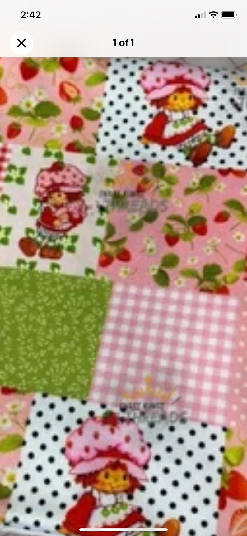 May include: A patchwork fabric featuring various patterns, including polka dots, gingham, and strawberry designs. The fabric showcases a repeating image of a cartoon strawberry character in a pink bonnet and red dress.