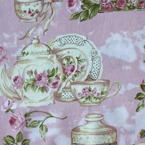 Könnte beinhalten: Rosa Blumengewebe mit Teetassen, Teekannen und Tellern mit rosa Rosenmustern. Ein dekoratives Glas mit dem Wort "Flowers" ist ebenfalls sichtbar. Der Stoff hat eine Vintage-Ästhetik im Cottagecore-Stil.