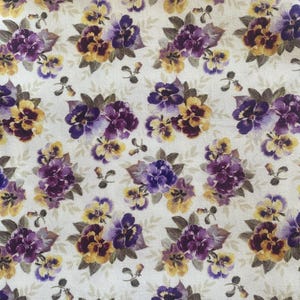 May include: Floral fabric featuring a repeating pattern of purple and yellow pansies with green leaves on a cream background. The pansies are clustered together, creating a dense and colorful design. This fabric is suitable for various sewing and crafting projects.