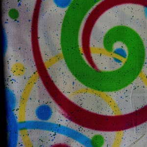 Puede incluir: Tela blanca con un diseño abstracto colorido con espirales y puntos en rojo, verde, amarillo y azul. El diseño tiene un efecto de pintura salpicada.