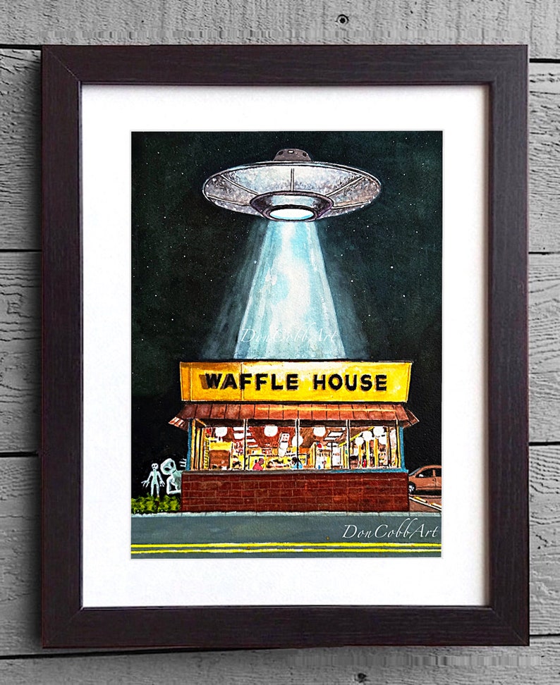 Puede incluir: Una pintura de acuarela de un OVNI flotando sobre un restaurante Waffle House por la noche. El OVNI est&aacute; proyectando una luz brillante sobre el edificio. Dos figuras alien&iacute;genas est&aacute;n de pie frente al restaurante. La pintura est&aacute; firmada "Don Cobb Art."