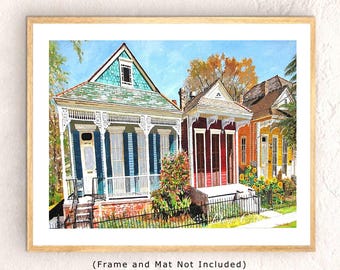 May include: Watercolor painting of colorful houses with intricate architectural details. The houses are painted in shades of blue, red, and yellow, with white trim and decorative elements. The artwork is framed in a light wood frame.