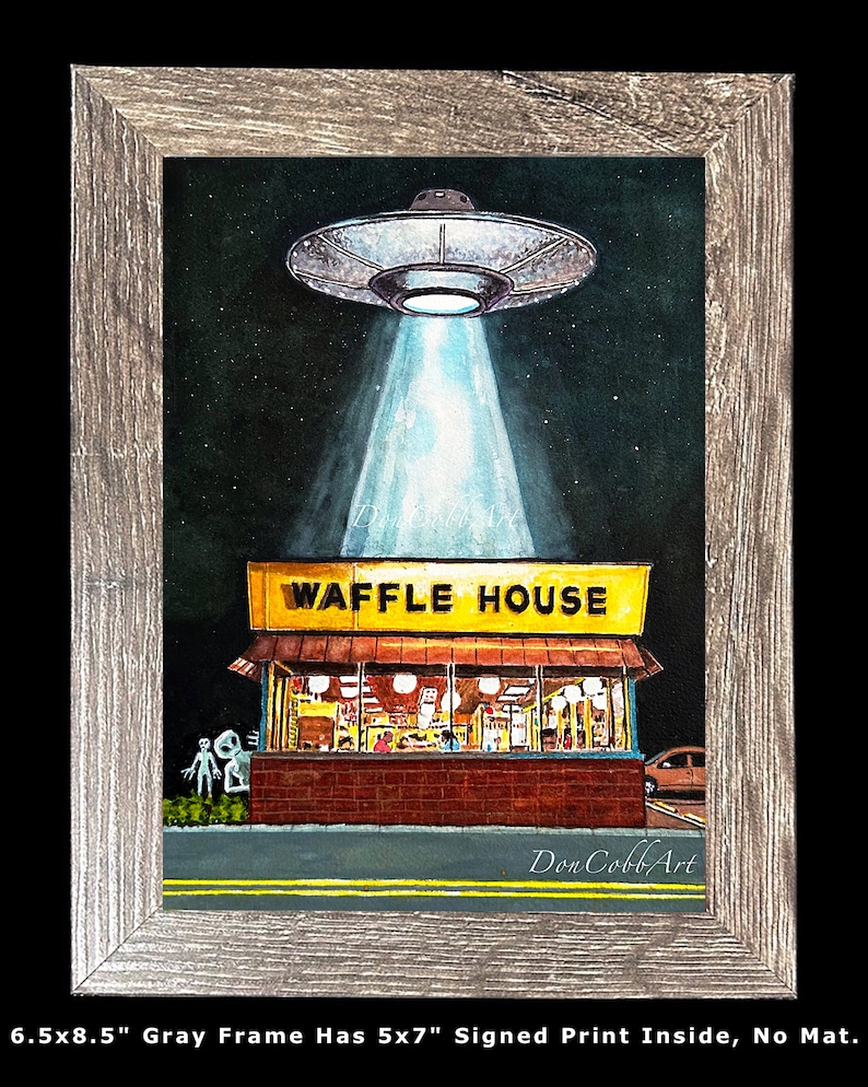 Puede incluir: Una pintura de acuarela de un OVNI sobrevolando un restaurante Waffle House. El OVNI est&aacute; emitiendo un rayo de luz. La pintura est&aacute; enmarcada en un marco de madera gris. La pintura mide 12,7x17,8 cm y est&aacute; firmada por el artista. El marco mide 16,5x21,6 cm.